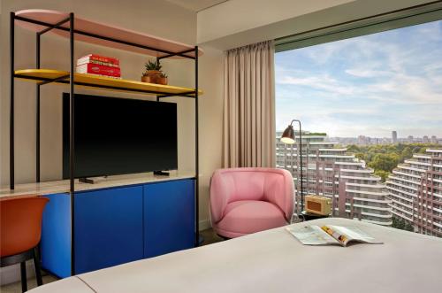 a hotel room with a tv and a pink chair at art'otel London Battersea Power Station, Powered by Radisson Hotels in London