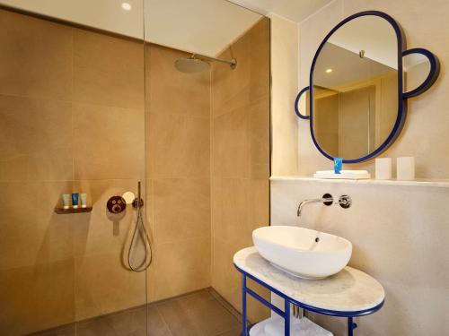 a bathroom with a sink and a shower with a mirror at art'otel London Battersea Power Station, Powered by Radisson Hotels in London