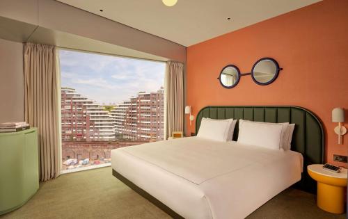 a bedroom with a large bed and a large window at art'otel London Battersea Power Station, Powered by Radisson Hotels in London