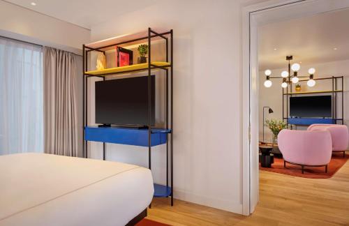 a bedroom with a bed and a living room with a table at art'otel London Battersea Power Station, Powered by Radisson Hotels in London