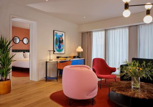 a living room with a pink chair and a desk at art'otel London Battersea Power Station, Powered by Radisson Hotels in London