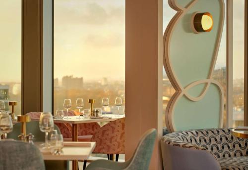 a restaurant with tables and chairs and a large window at art'otel London Battersea Power Station, Powered by Radisson Hotels in London