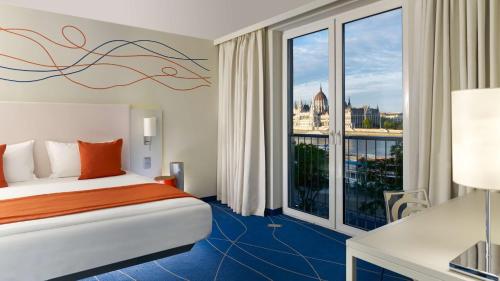 a hotel room with a bed and a large window at Park Plaza Budapest in Budapest