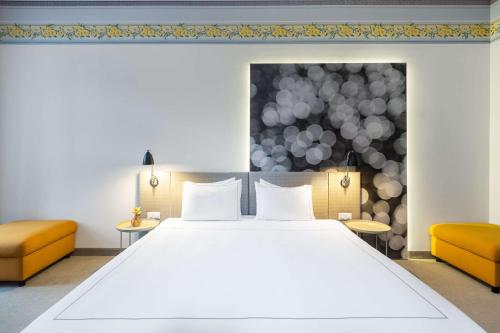 a bedroom with a large bed and two orange chairs at Park Plaza Budapest in Budapest