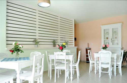 a dining room with white tables and white chairs at Triantafilia Guesthouse in Áyioi Apóstoloi
