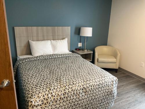 a bedroom with a bed and a chair and a lamp at WoodSpring Suites East Lansing - University Area in East Lansing