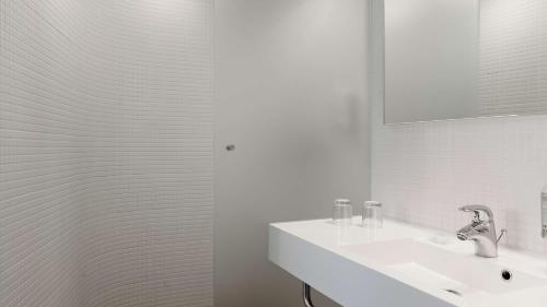 a white bathroom with a sink and a mirror at Park Plaza Amsterdam Airport in Lijnden