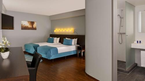 a hotel room with two beds and a table at Park Plaza Amsterdam Airport in Lijnden