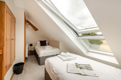 a attic bedroom with two beds and two windows at Buttercup Cottage in Salisbury