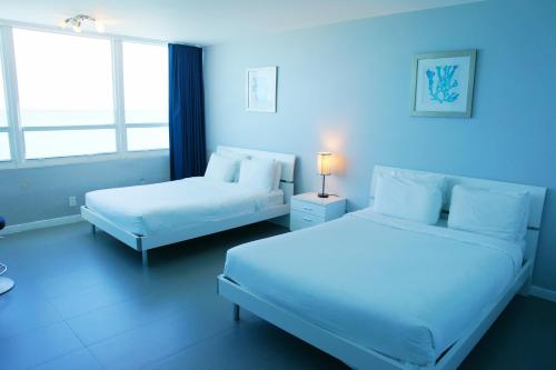 a blue room with two beds and a window at Castle 835 Oceanview studio on beach with pool, gym, bars, and FREE Parking in Miami Beach