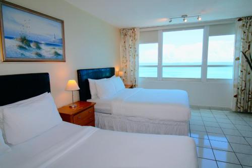 um quarto de hotel com duas camas e uma janela em Ocean view studio with direct beach access and a shared pool & tennis court! em Miami Beach