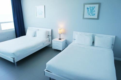 two beds in a room with white sheets and pillows at Castle 835 Oceanview studio on beach with pool, gym, bars, and FREE Parking in Miami Beach