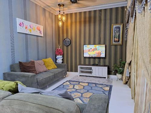 ein Wohnzimmer mit einem Sofa und einem TV in der Unterkunft Homestay Machang - Lycaste Inn Muslim in Macang