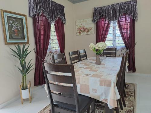 ein Esszimmer mit einem Tisch, Stühlen und roten Vorhängen in der Unterkunft Homestay Machang - Lycaste Inn Muslim in Macang
