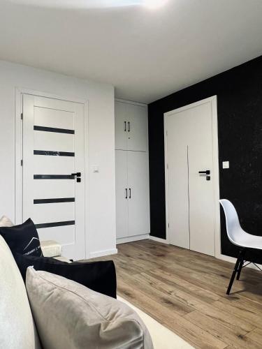 a living room with white cabinets and a black wall at Apartamenty Modrzewiowa Zator in Piotrowice