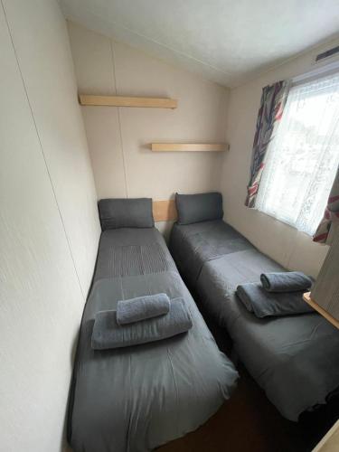 a small room with two beds and a window at Fantasy Island, Sunnymede 8 Berth in Ingoldmells