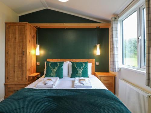 a bedroom with a large bed with green walls at Buttercup in Swadlincote