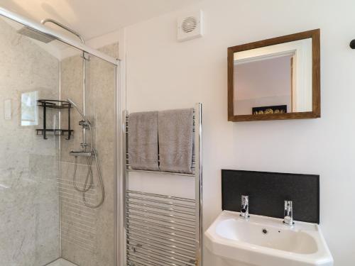 a bathroom with a shower and a sink and a mirror at Juniper in Swadlincote