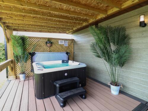 a bath tub on a wooden deck with plants at Juniper in Swadlincote