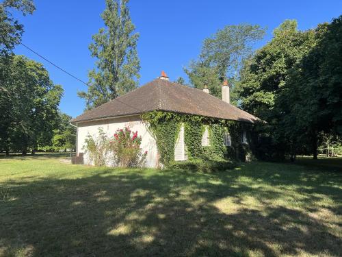 um pequeno edifício branco com hera num campo em La Petite Trolière em Orval