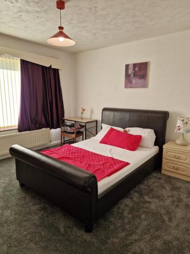 una camera da letto con un letto grande con una coperta rossa di Chimes-Company & Family Stay, 2 Bedroom House + Free parking a Tamworth