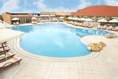 a large swimming pool in a resort with lounge chairs at Hilton Alexandria Green Plaza in Alexandria