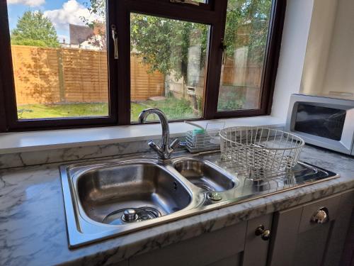a kitchen sink with a window and a microwave at Chimes-Company & Family Stay, 2 Bedroom House + Free parking in Tamworth