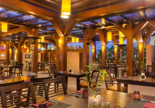a restaurant with wooden tables and chairs and lights at Hilton Alexandria Green Plaza in Alexandria
