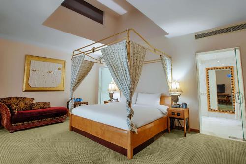 a bedroom with a canopy bed and a couch at Hilton Alexandria Green Plaza in Alexandria