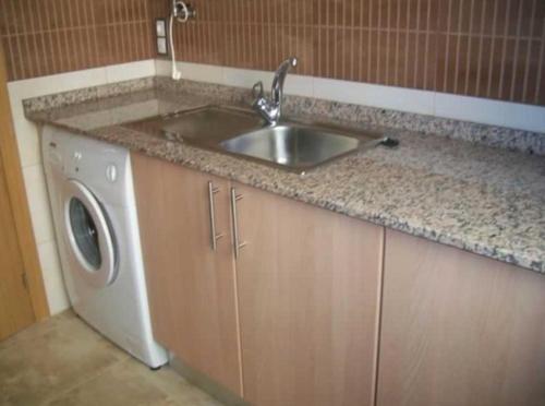 a kitchen with a sink and a washing machine at Apartamentos Albamar II in Calpe