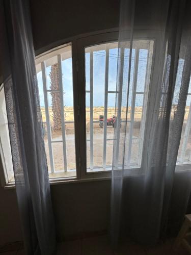 a window with white curtains and a view of the beach at sea View Nautilus free wi-fi Sal Rei in Sal Rei