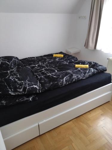 a bed with a black comforter on top of it at Tókert Apartman in Ráckeve