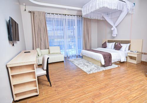 ein Schlafzimmer mit einem Bett, einem Schreibtisch und einem Fernseher in der Unterkunft Hotel Next in Masaka