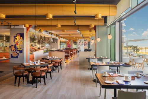 un restaurante con mesas y sillas y una cafetería en The WB Abu Dhabi, Curio Collection By Hilton, en Abu Dabi