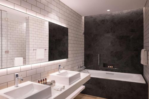 a bathroom with two sinks and a tub and a mirror at The WB Abu Dhabi, Curio Collection By Hilton in Abu Dhabi