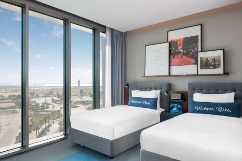 two beds in a room with large windows at The WB Abu Dhabi, Curio Collection By Hilton in Abu Dhabi