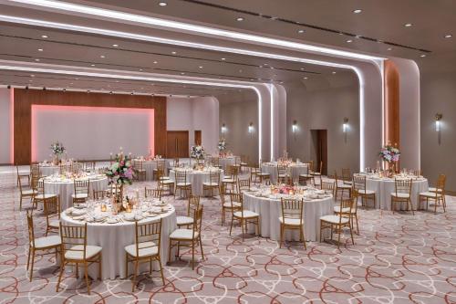 a banquet hall with tables and chairs and a projection screen at The WB Abu Dhabi, Curio Collection By Hilton in Abu Dhabi