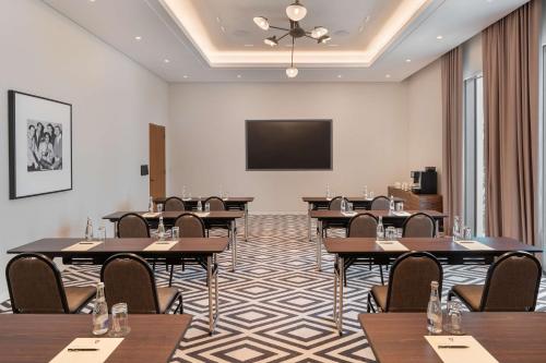 a conference room with tables and a flat screen tv at The WB Abu Dhabi, Curio Collection By Hilton in Abu Dhabi