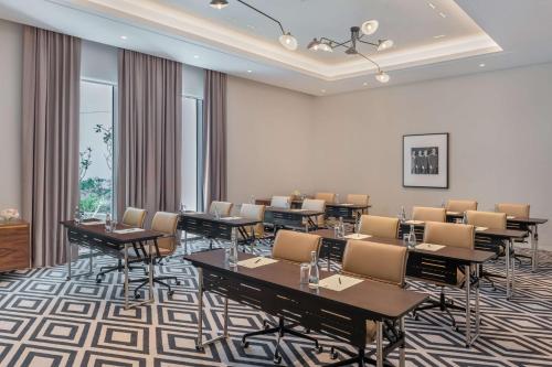 a conference room with tables and chairs and windows at The WB Abu Dhabi, Curio Collection By Hilton in Abu Dhabi