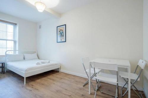 Cette chambre blanche comprend un lit, une table et une chaise. dans l'établissement APlaceToStay Central London Apartment, Zone 1 COV, à Londres