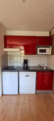 a kitchen with red cabinets and a white microwave at Résidence Goélia Les Gorges de la Truyère in Entraygues-sur-Truyère