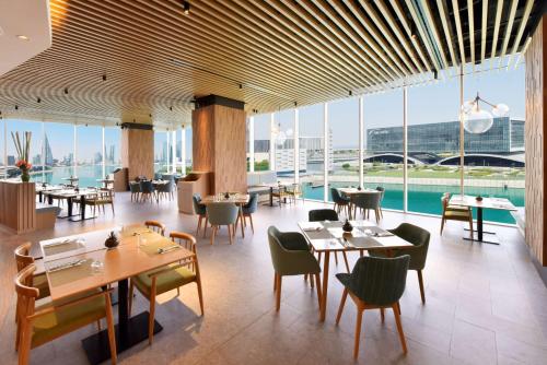 a restaurant with tables and chairs and large windows at Hilton Garden Inn Bahrain Bay in Manama