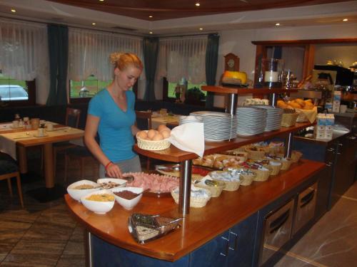 a woman standing at a counter with a buffet of food at Hotel Maibad in Vipiteno