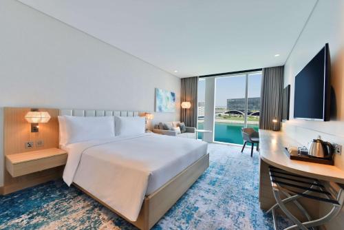 Hilton Garden Inn Bahrain Bay في المنامة: غرفة الفندق بسرير كبير ومكتب