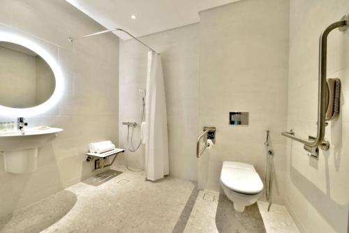 a white bathroom with a toilet and a sink at Hilton Garden Inn Bahrain Bay in Manama