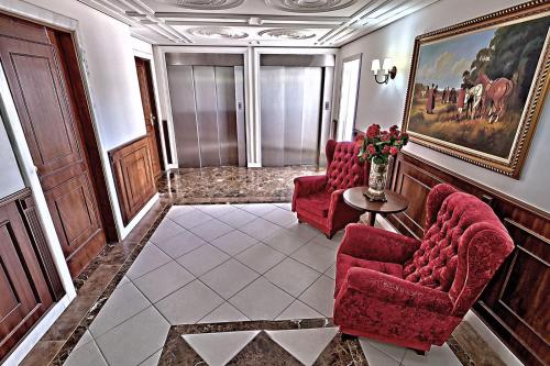 a room with two red chairs and a vase of flowers at Hotel Firenze in Serra Negra