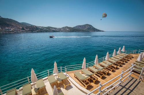 a group of beach chairs and a boat in the water at Likya Gardens Hotel in Kas
