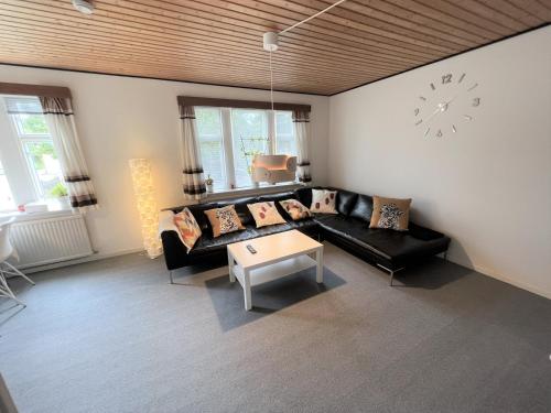 a living room with a couch and a clock on the wall at The Yellow House, Beach 5mins Drive, 3BR with free parking, Fast Fiber Internet in Rødby