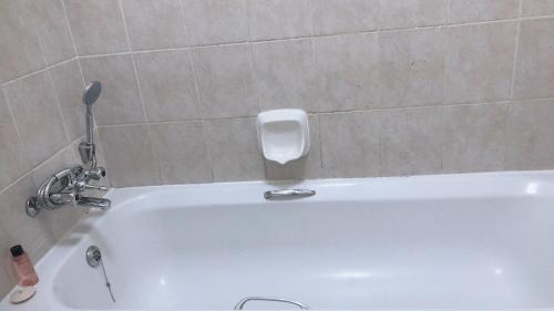 a white bath tub with a soap dispenser in a bathroom at Menlyn Place Staycation in Pretoria