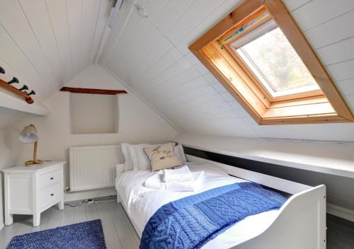 um pequeno quarto no sótão com uma cama e uma janela em 1 Browcote Cottage em Ravenscar